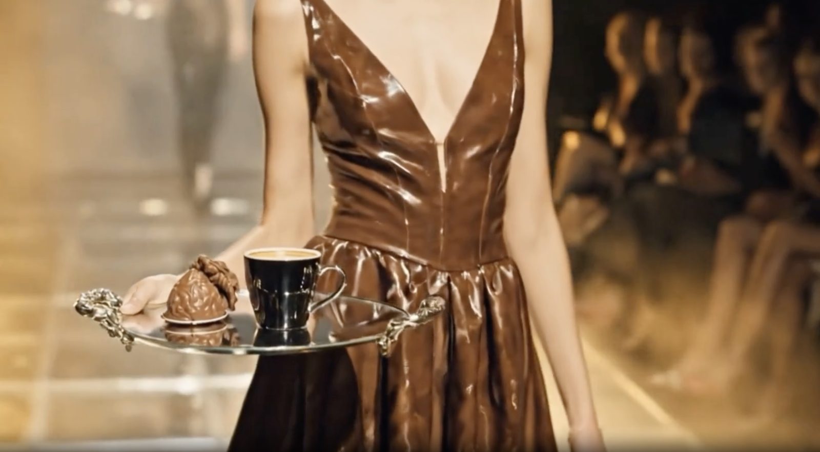 A model on a golden runway in a sculpted chocolate gown.