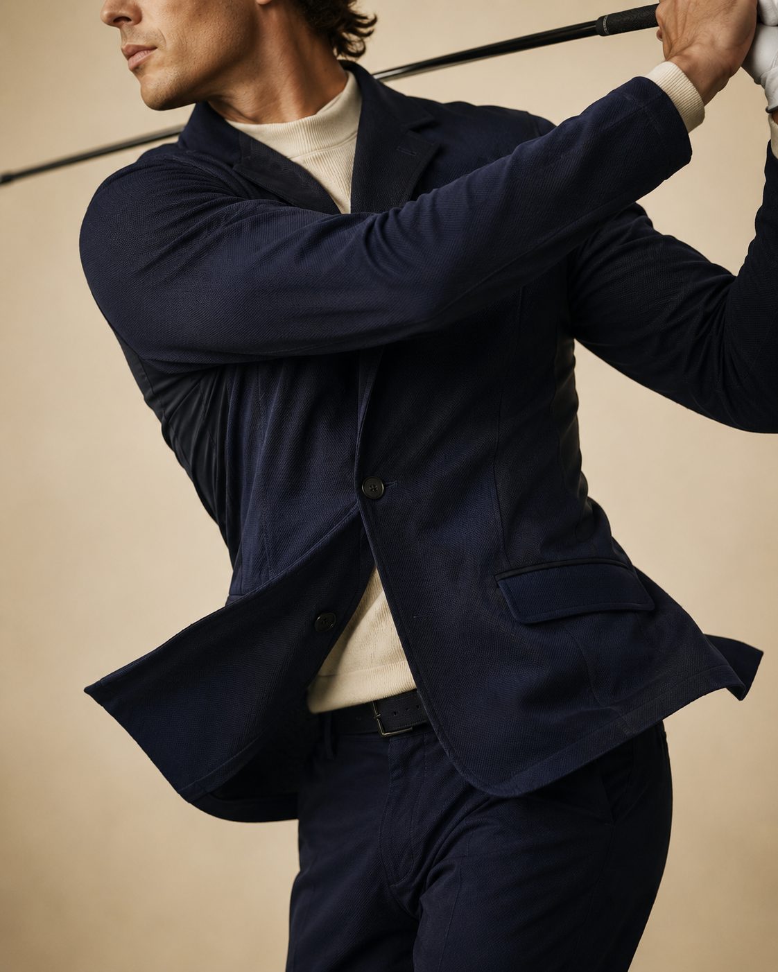Product proof — a navy tailored jacket mid-swing, stretching and moving with the body.